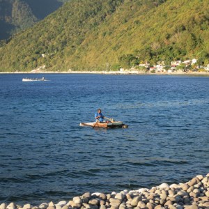 A simple raft built of scraps of wood. It doesn't have much speed but floats and is working for this fisherman.