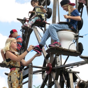 While the children rode around, a ferris wheel attendant playfully tried to steal shoes, hats, or anything she could reach from the children.