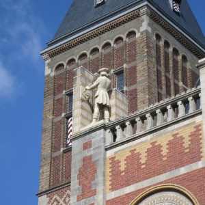 Statue of an artist working on the enormous art museum, Rijksmuseum.