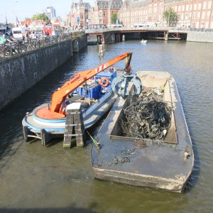 Canal cleaning. The orange machine digs into the water and picks up bicycles that were thrown over. While we watched, they scooped out about 8 mangled bicycles.