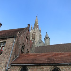 One of the beautiful spires in Bruges peaks over closer rooflines.