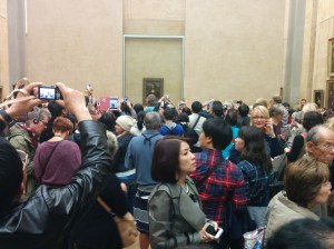 With her dark hair and enigmatic smile, this woman moves through a crowd focused on some famous painting.