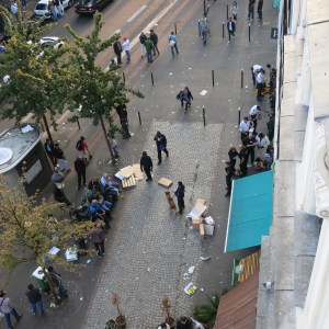Police raiding the black market. Note the officer with the dog and the line of men detained up against the wall on the right. Also notice how the large crowd is gone!