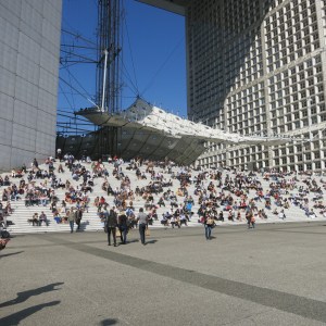 Business lunch crowd on the steps of La Défense arch. The parabolic object in the center is a wind deflector.