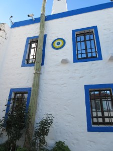 A typical Bodrum house with blue trim, white walls, and protection from the evil eye. Note the extremely tall cactus!